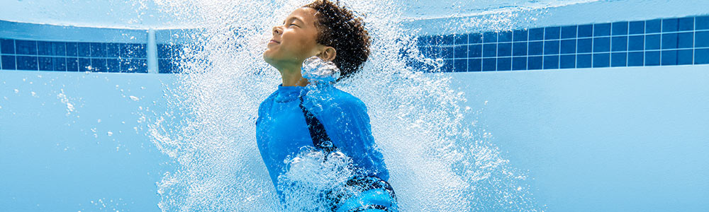 boy emerging through water bubbles in pool